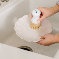 Someone using their Nellies dish stick to clean a dish