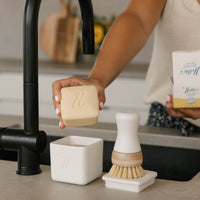 Nellies dish butter and forever brush sitting on a kitchen counter next to a sink