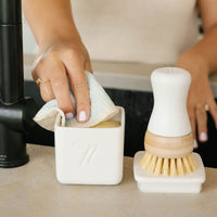 nellies dish butter and nellies forever brush on a kitchen counter next to a sink