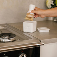 nellies dish butter and nellies forever brush being used to clean a stove top