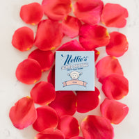 Nellie's Rose Scented Dryerball packaging on a bed of roses