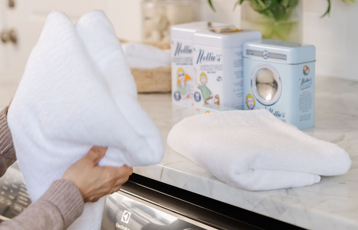 A person folding laundry in a laundry room.