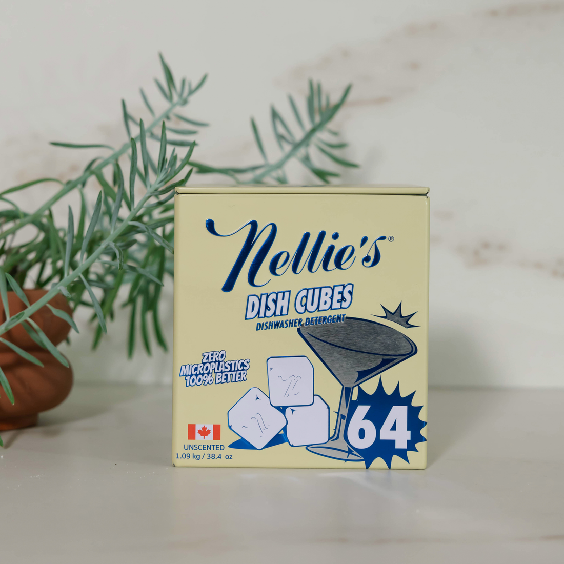 A box of Nellie's Dish Cubes uncentrated ice cubes, size 64, standing on a light marble surface with a green plant in the background.