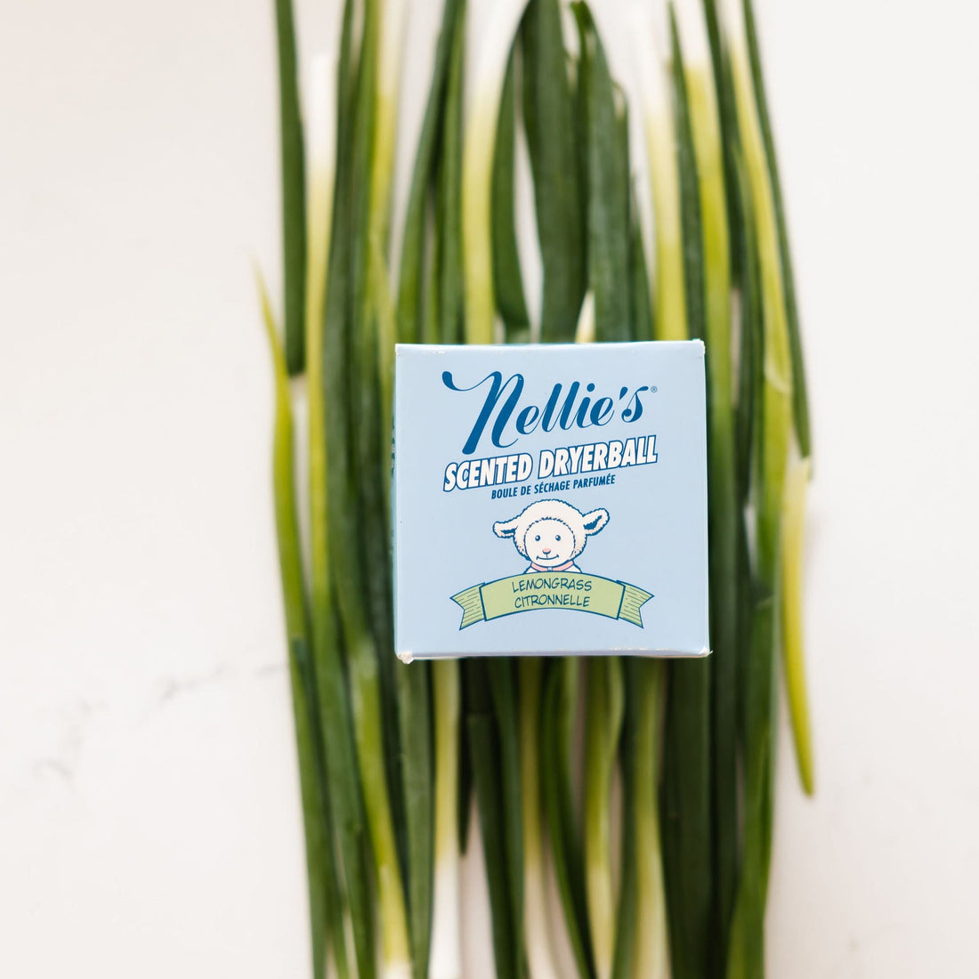 Nellie's Lemongrass Scented Dryerball packaging on a bed of lemongrass