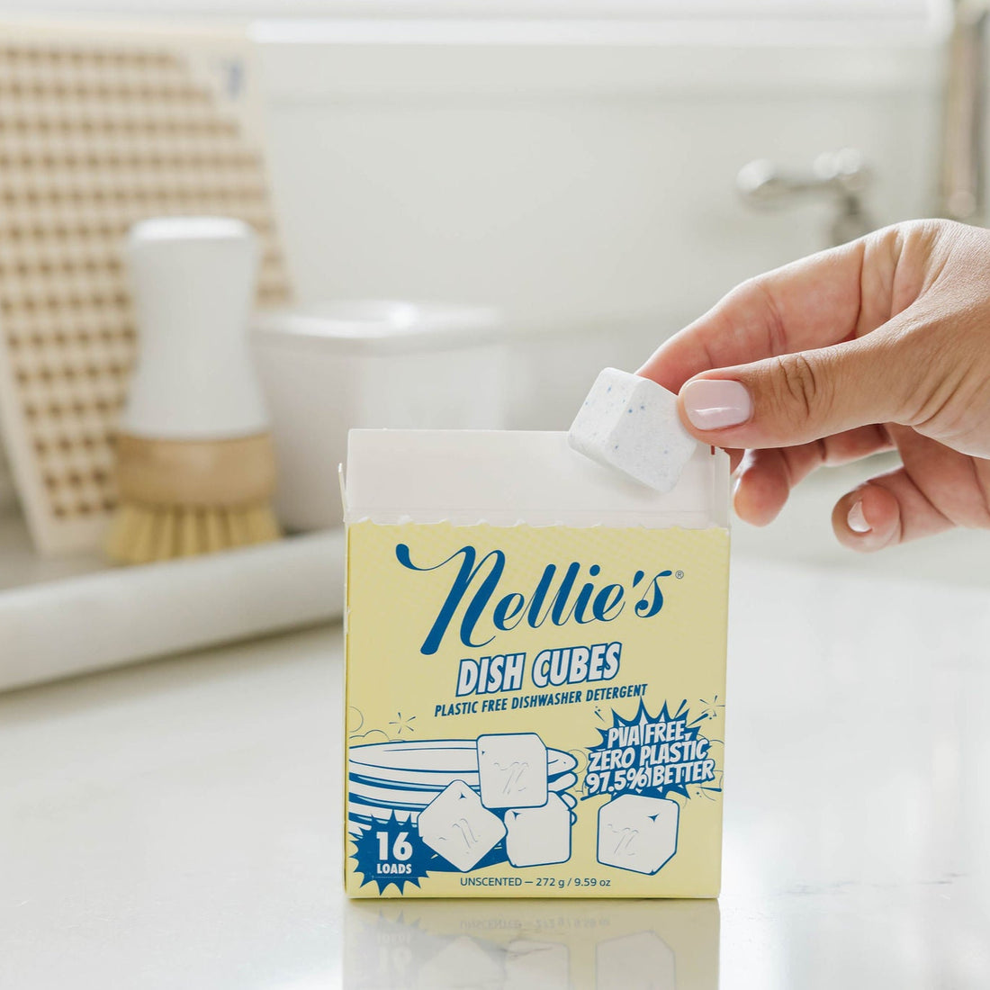 Person holding a box of Nellie's Dish Cubes in a kitchen setting