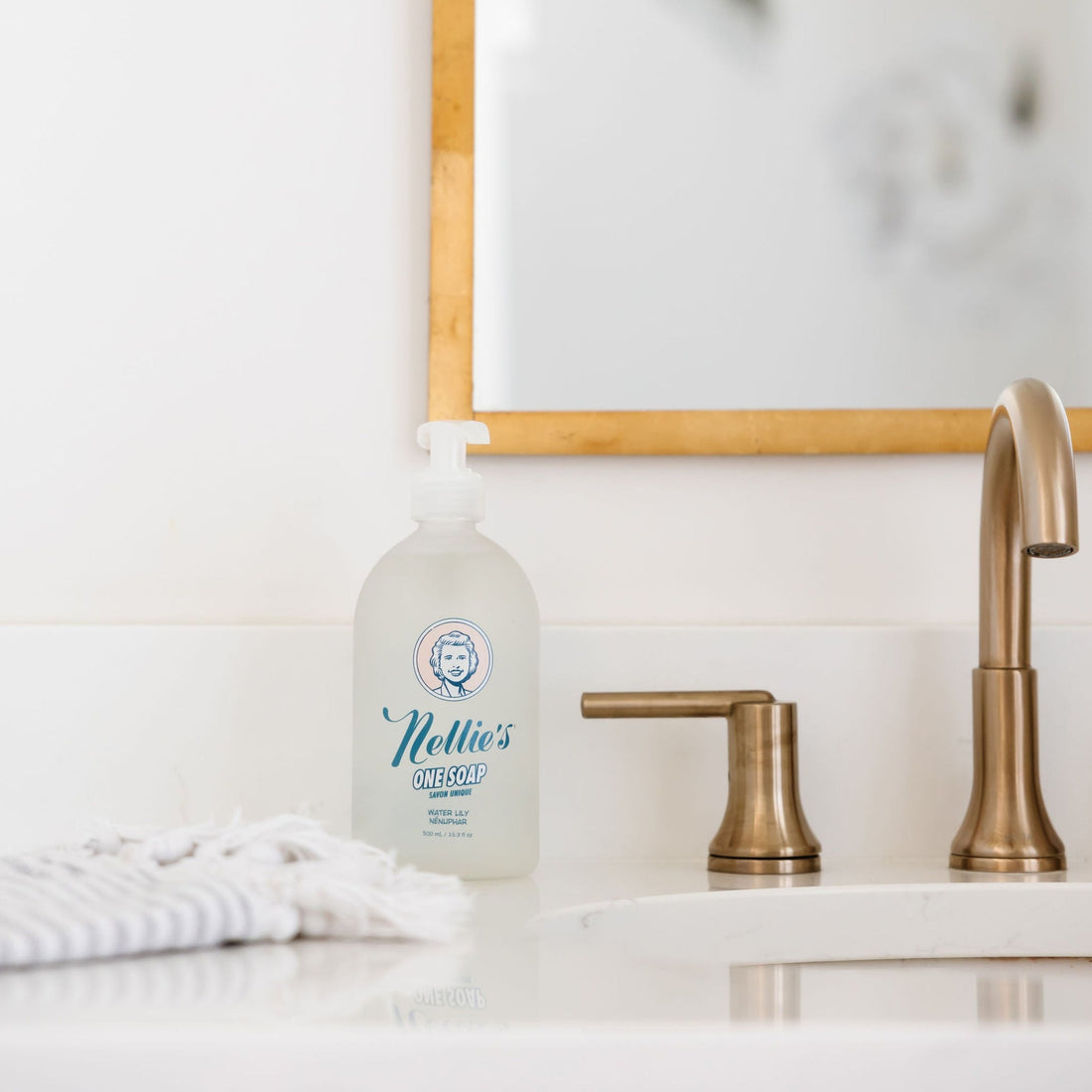 Nellie's glass multi-use One Soap glass bottle with pump on Bathroom counter by sink